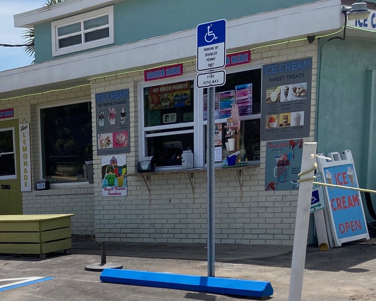 Image of ADA-compliant handicap parking space with signage in front of ice cream shop